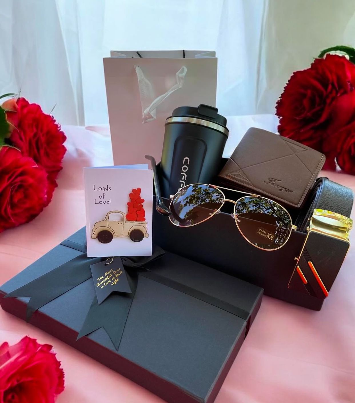 Collection of gifts including a wallet and a card on a pink surface